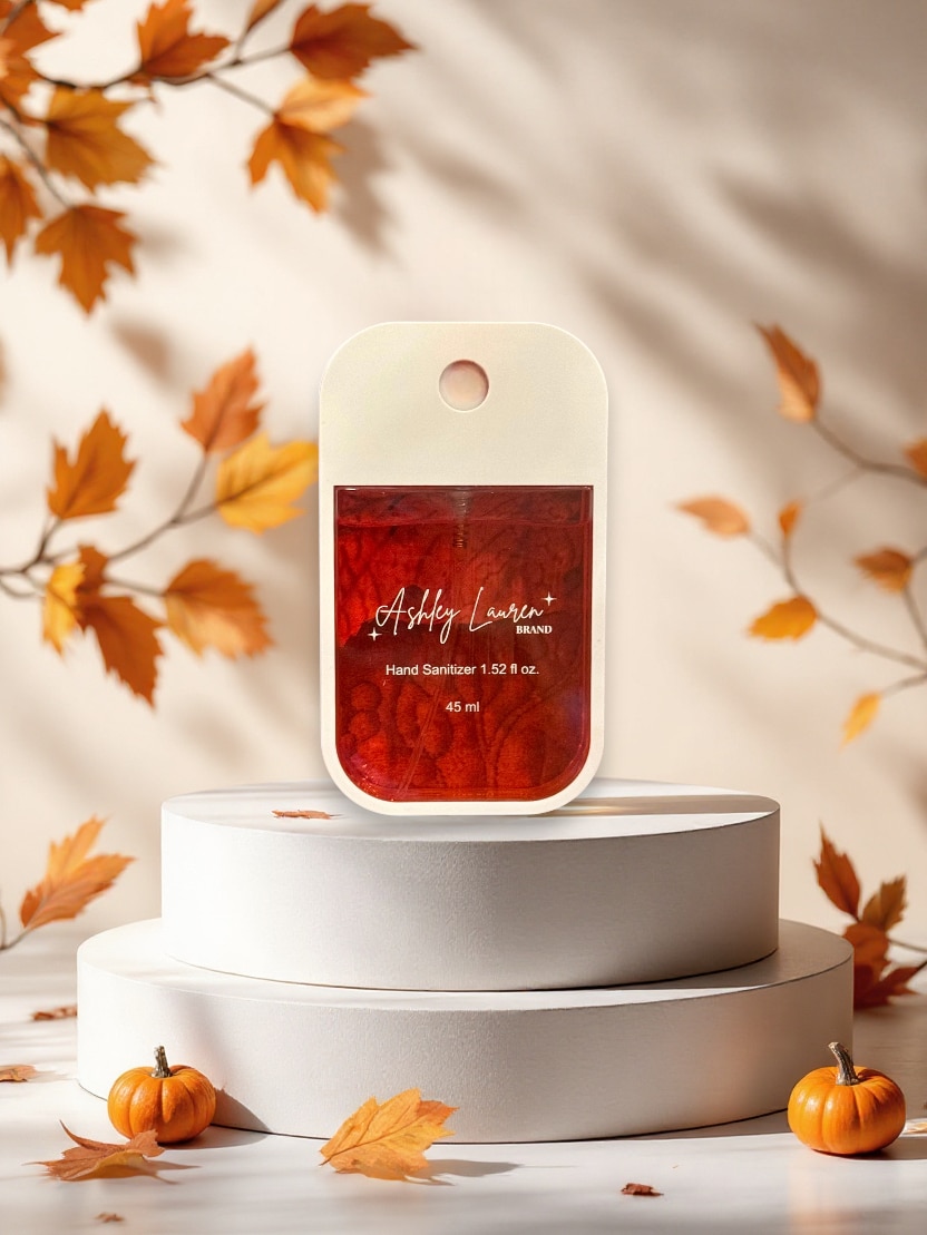 Apple Cinnamon Hand Sanitizer Spray in slim white case with bold red liquid, styled with pumpkins and fall leaves.