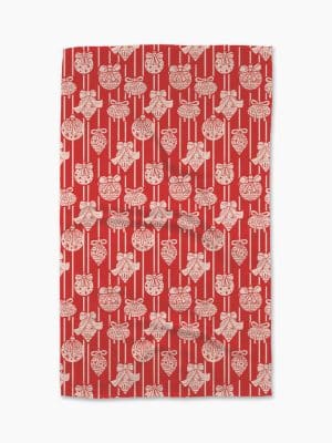 Red holiday kitchen towel with festive white ornaments and bows, made from absorbent Geometry Geoweave™ fabric.