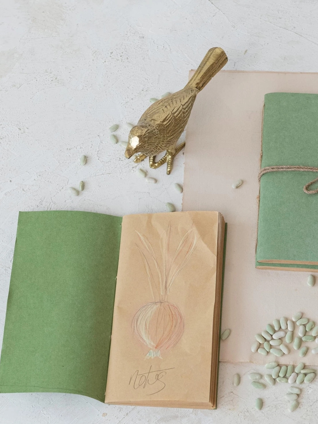 Textured Gold Bird Figurine with detailed feathering in a warm gold finish, styled near green notebooks and desk accessories.