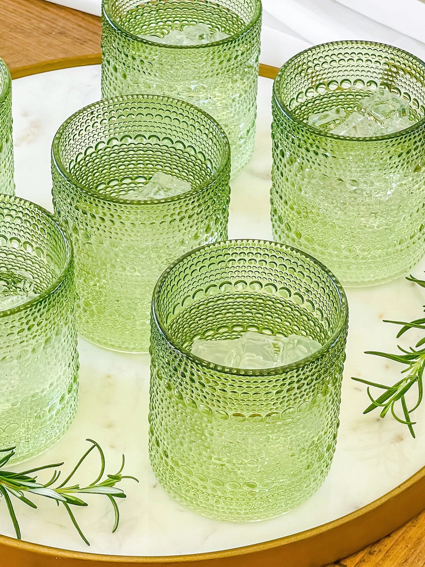 Set of sage green beaded old fashion glasses styled together on a tray.