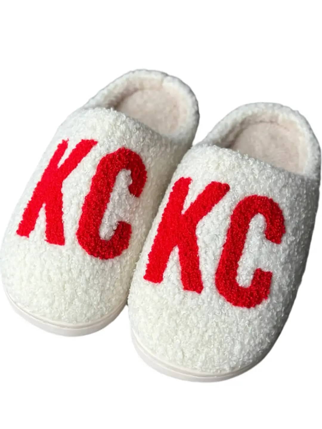 White sherpa-style slippers with bold red “KC” lettering, designed for Kansas City fans and cozy game day comfort.