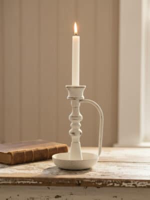 Vintage Chamberstick Taper Candle Holder styled with a lit taper candle beside a book