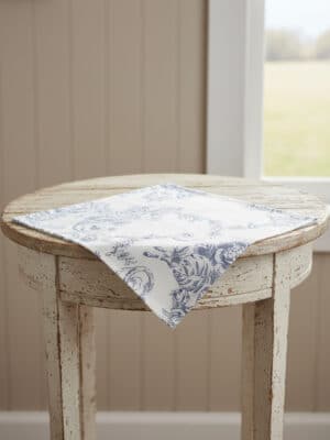 Blue Toile Square Table Runner styled on a distressed round table, folded corner-forward to show the pattern.