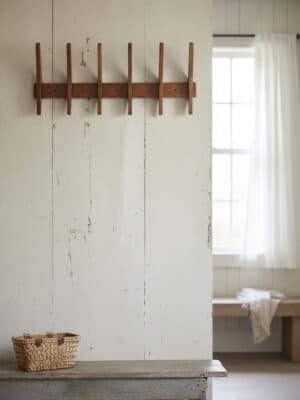 Large wood wall rack with five rounded pegs mounted on a white paneled wall, styled minimal and ready for coats, bags, or towels.
