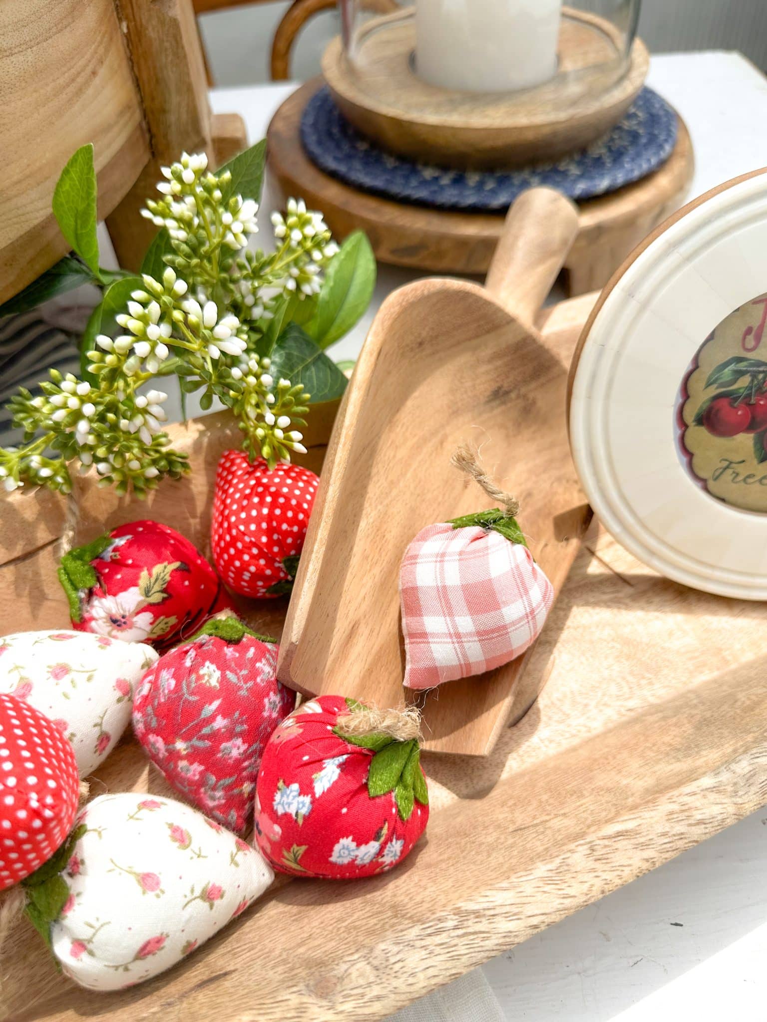 Close-up of pink gingham and floral fabric strawberries inside a carved wooden scoop.
