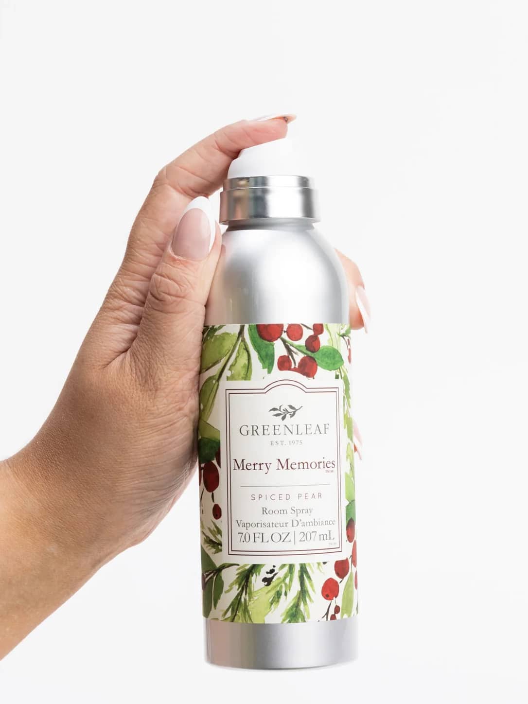 Hand holding a Greenleaf Merry Memories Room Spray air freshener with holiday-inspired packaging.