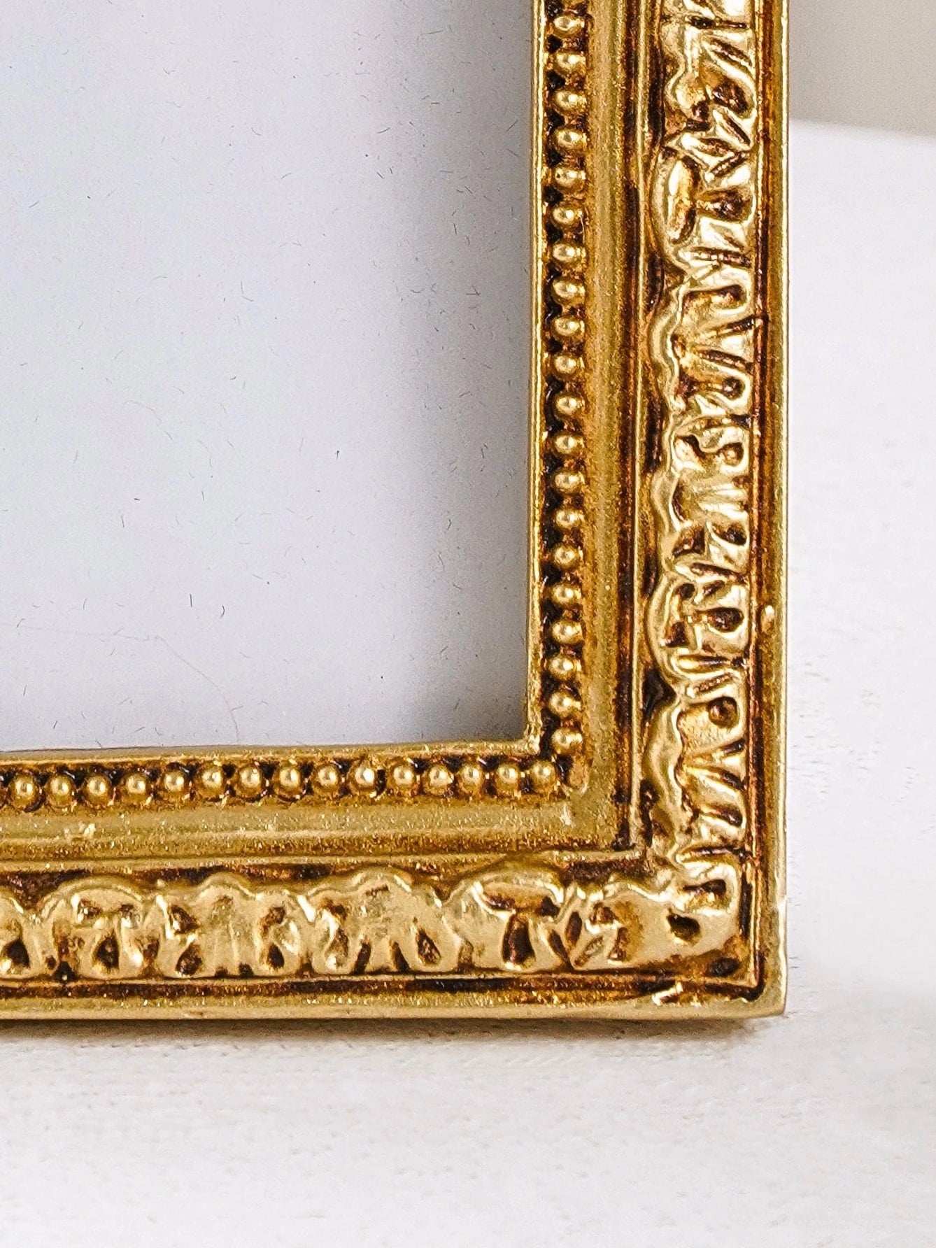 Gold ornate arch photo frame corner detail showing carved baroque trim and beaded edging.