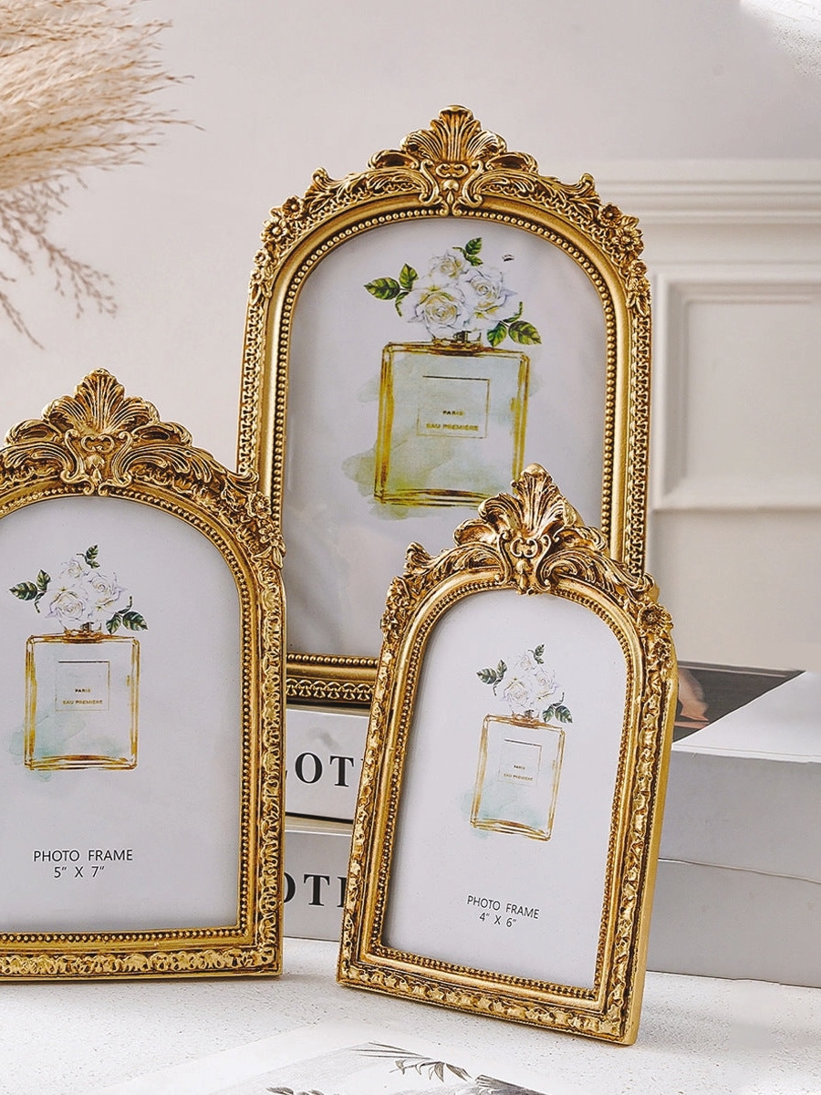Layered gold ornate arch photo frames styled together on a tabletop for a vintage-inspired look.