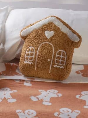 Festive gingerbread pillow styled on a bed with gingerbread-themed bedding.