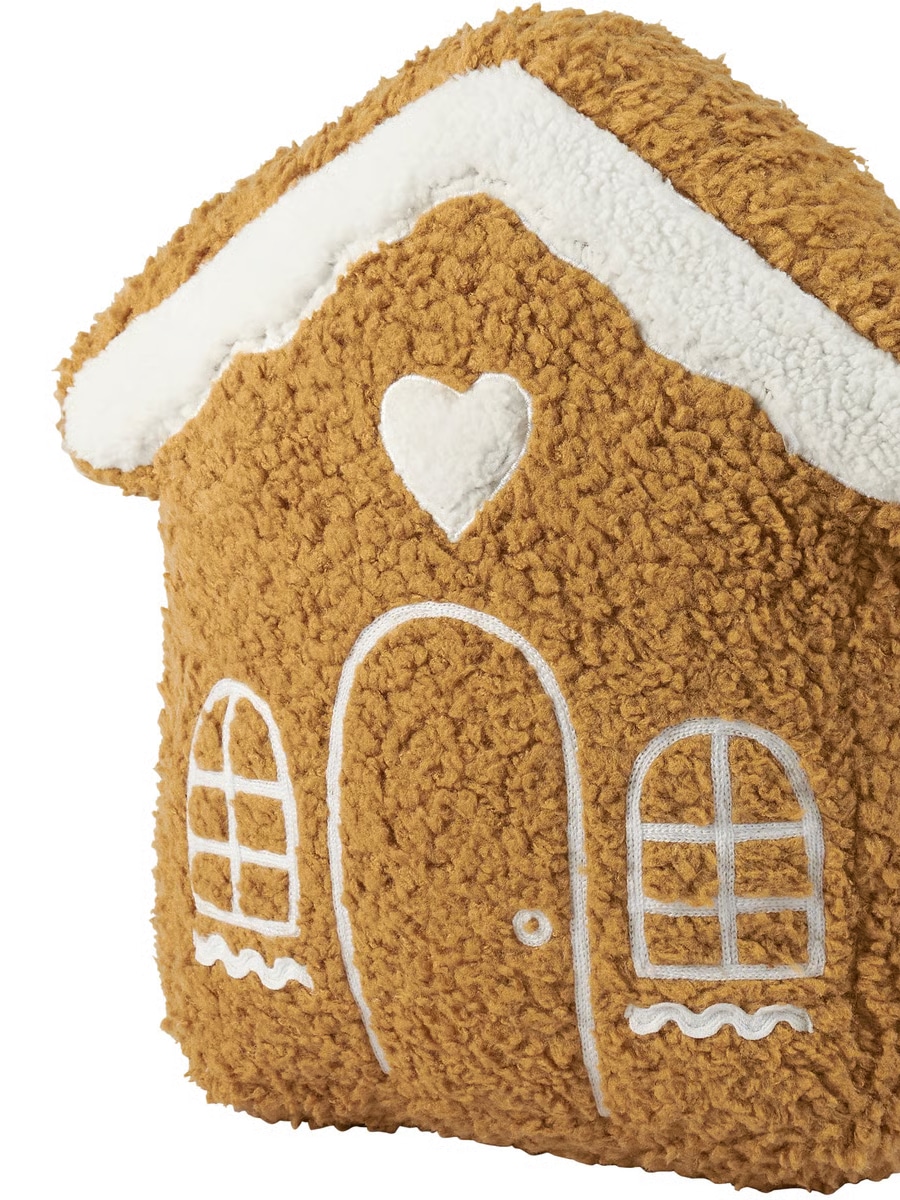 Gingerbread house-shaped pillow with embroidered windows, door, and heart detail.