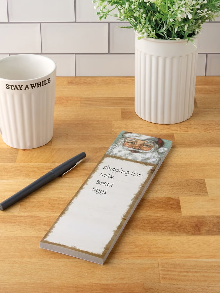 Magnetic Santa list notepad displayed on kitchen counter with pen.