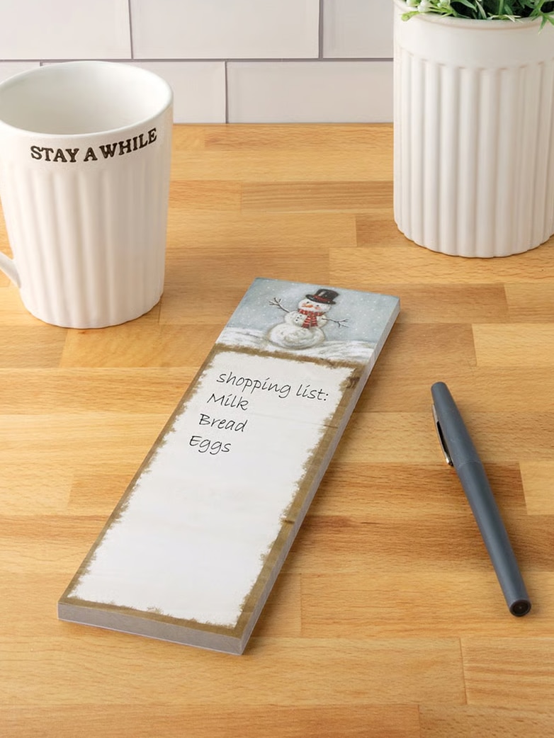 Festive snowman notepad displayed on kitchen counter with pen.