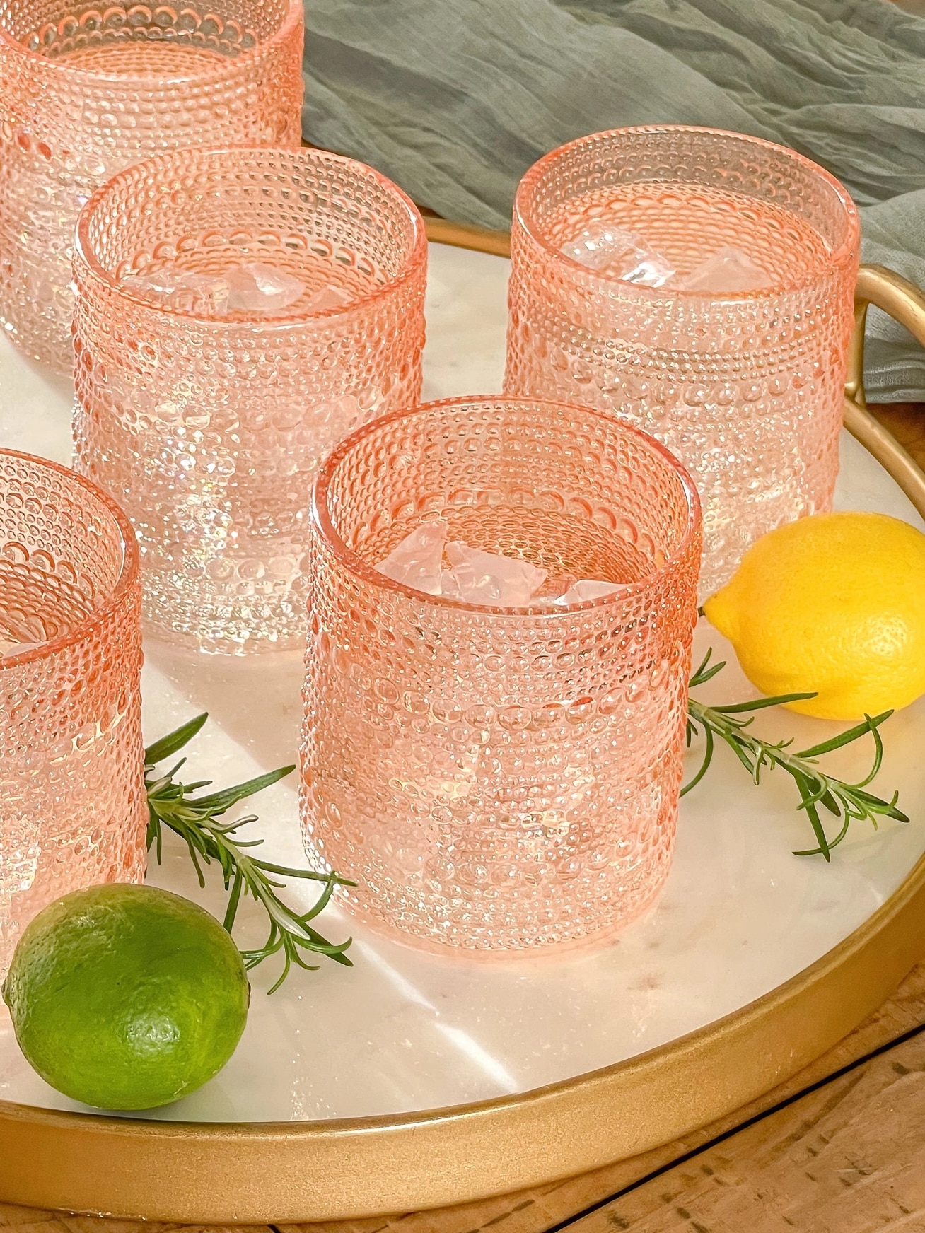 Set of rose gold beaded old fashion glasses styled with lemons and limes on a tray.