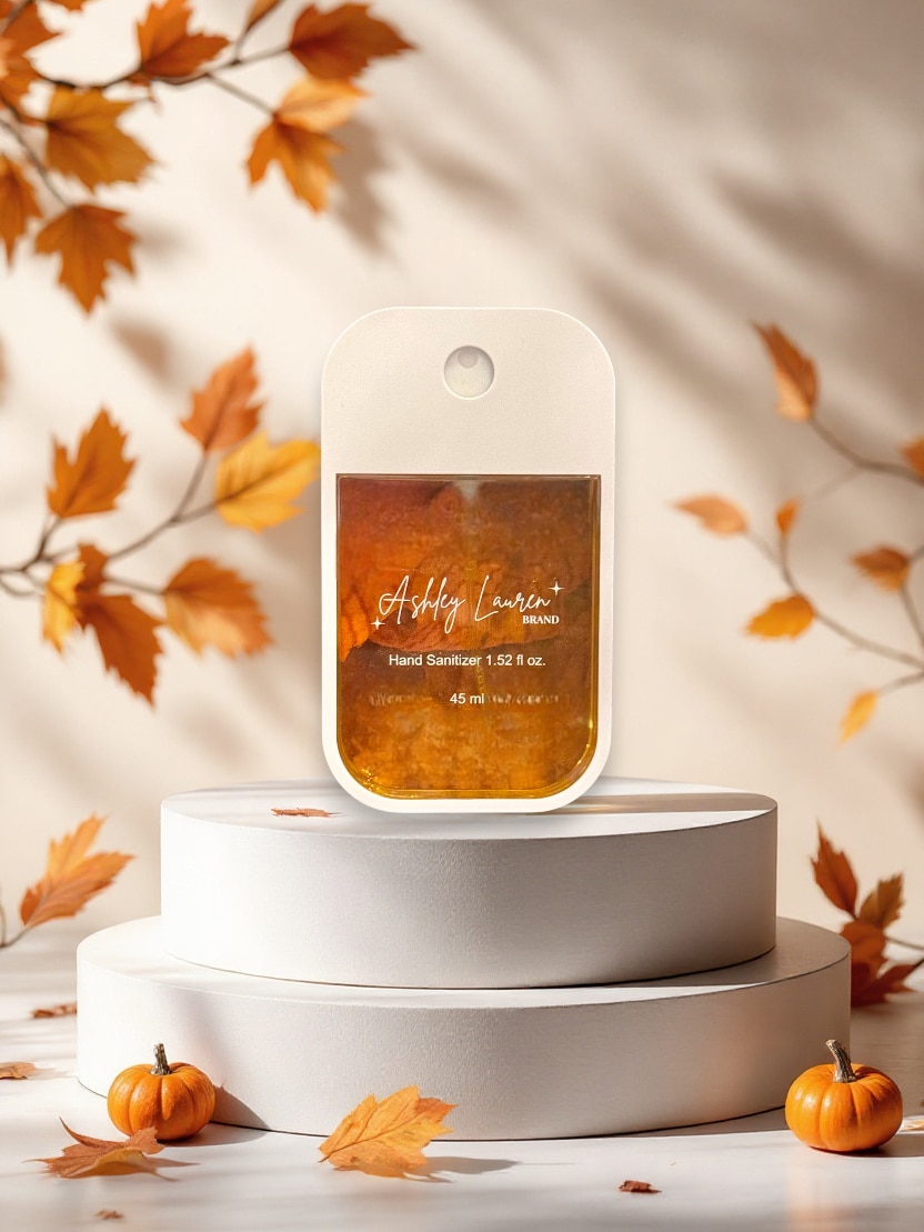 Pumpkin Hand Sanitizer Spray in sleek white case with orange liquid, styled with fall leaves and mini pumpkins.