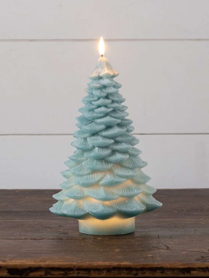 Light green 3D spruce tree flameless candle glowing warmly on a tabletop