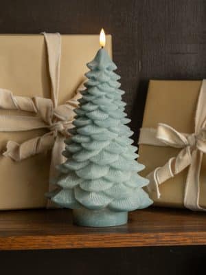 Light green 3D spruce tree flameless candle glowing beside wrapped holiday gifts