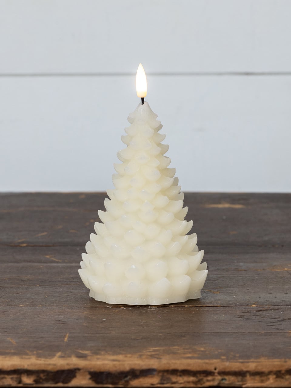 Cream 3D balsam tree flameless candle glowing on a wooden tabletop