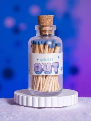 Mini Apothecary Vintage Chill Out Matches in a clear glass jar with cork top, soft blue match tips, and a retro-style “Chill Out” label against a blue and purple background.