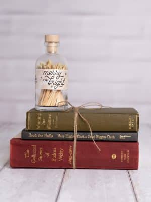 Vintage match jar labeled “Merry & Bright” styled on top of a twine-tied Decorative Vintage Book Set – Christmas with festive covers