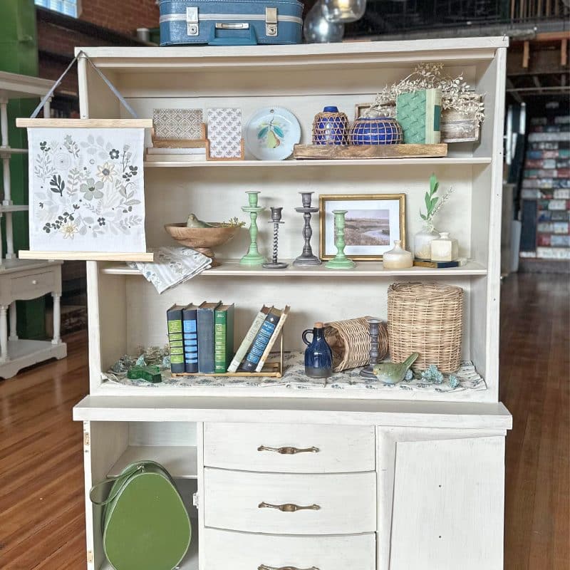 A cottagecore styled hutch with charming pieces. front view.
