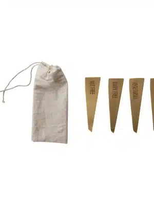 Set of four brushed brass food markers labeled "Nut Free," "Dairy Free," "Vegetarian," and "Gluten Free," shown with a cotton drawstring storage pouch.