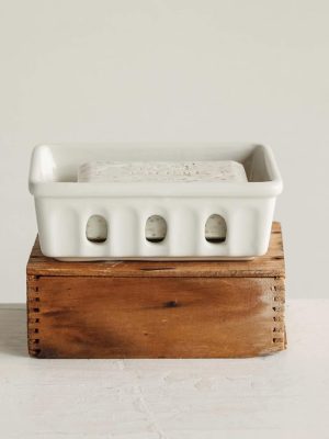 White stoneware berry bowl or soap dish with oval cutouts, displayed with a bar of soap on a wooden pedestal.