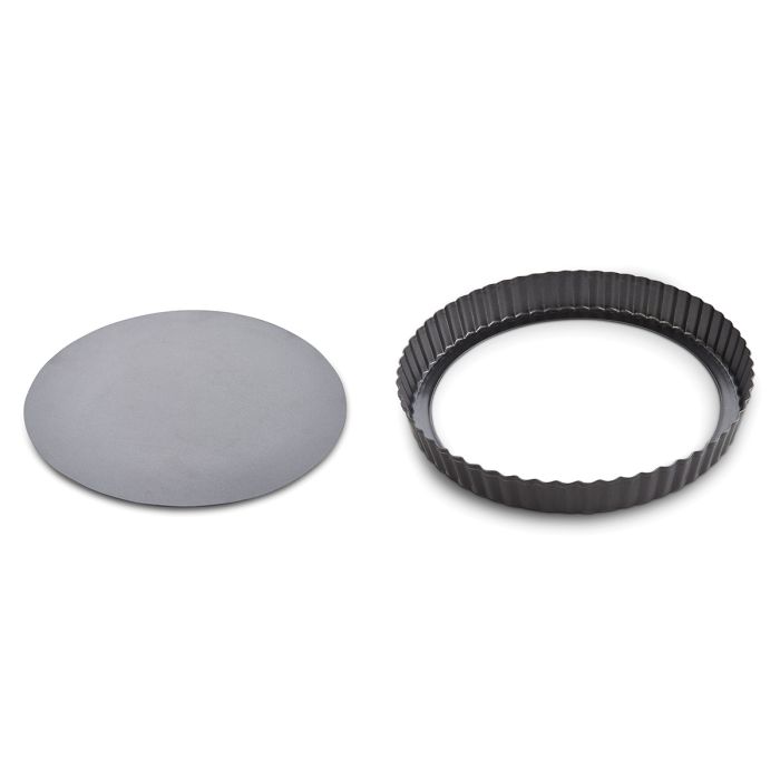 Hand holding removable base of a black nonstick tart pan next to the fluted ring