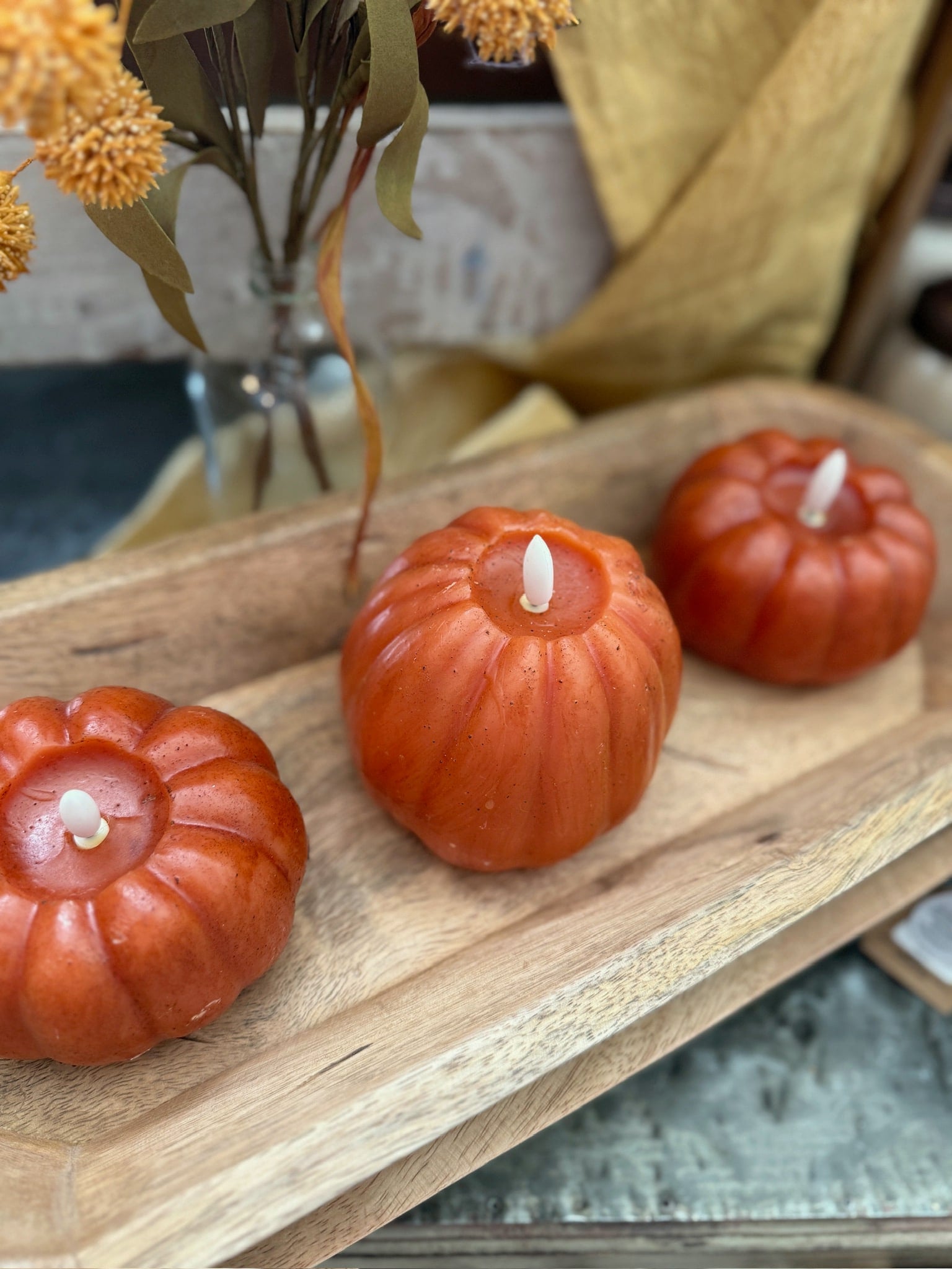 Orange pumpkin flameless candle with lifelike flickering flame in wooden tray