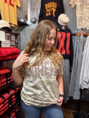Model wearing natural camo CHIEFS graphic tee with raised puff ink lettering.