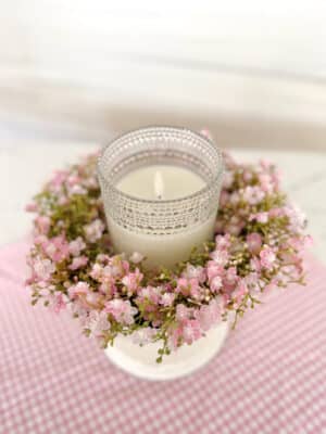 Close-up of a clear dotted glass flameless candle inside a Pink Stardust Blooms Candle Ring styled in a white pedestal bowl.