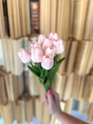 Handheld bundle of light pink faux tulips with green leaves, featuring nine stems and delicate spring blooms.
