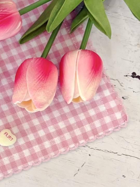 Bright Pink Tulips resting on a Pink Gingham Square Table Runner, showcasing vivid petals against a classic check pattern.