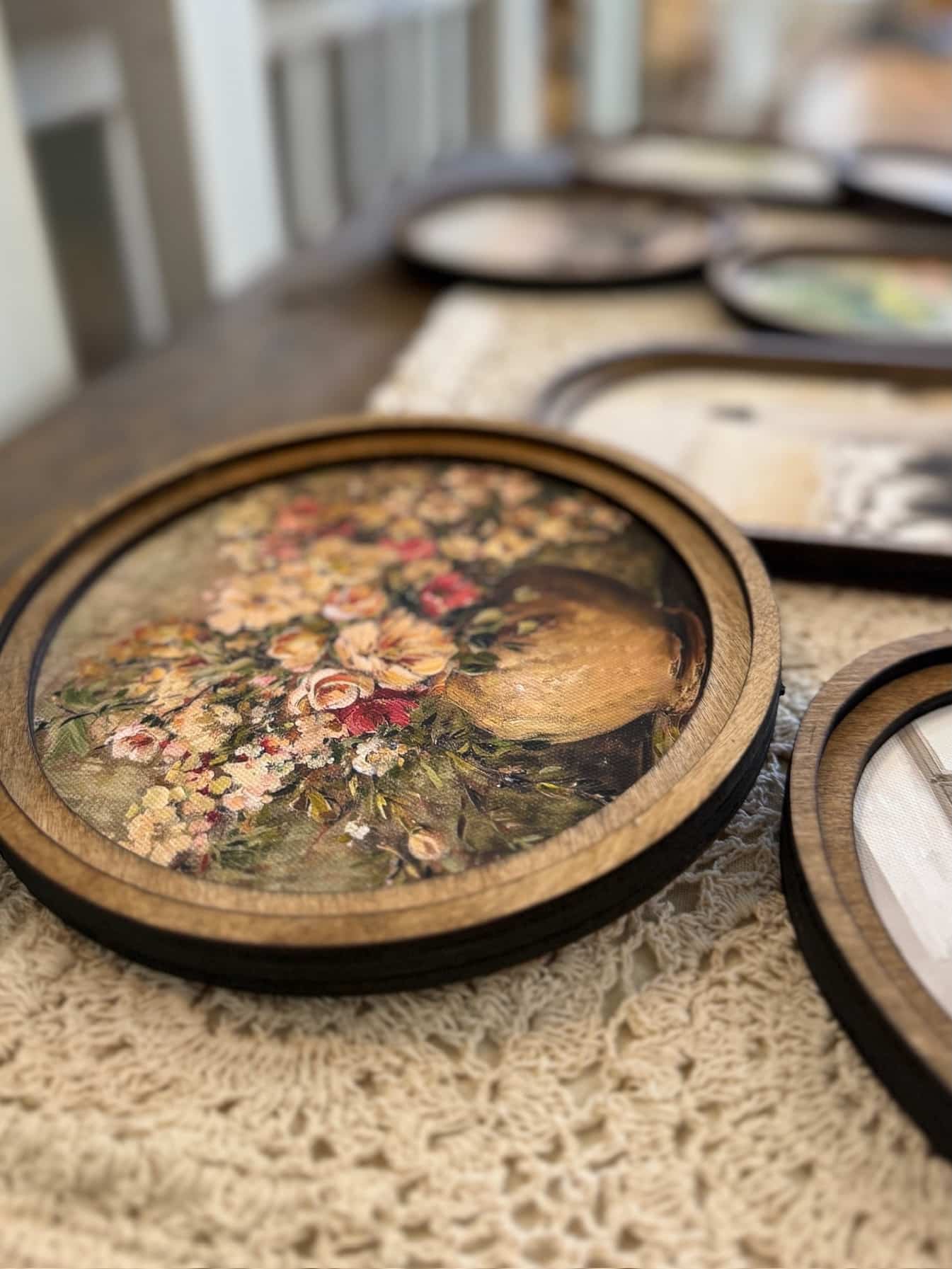 Close-up of round floral canvas wall art with double-layered wood frame, showing detailed vintage flowers in a rustic vase.