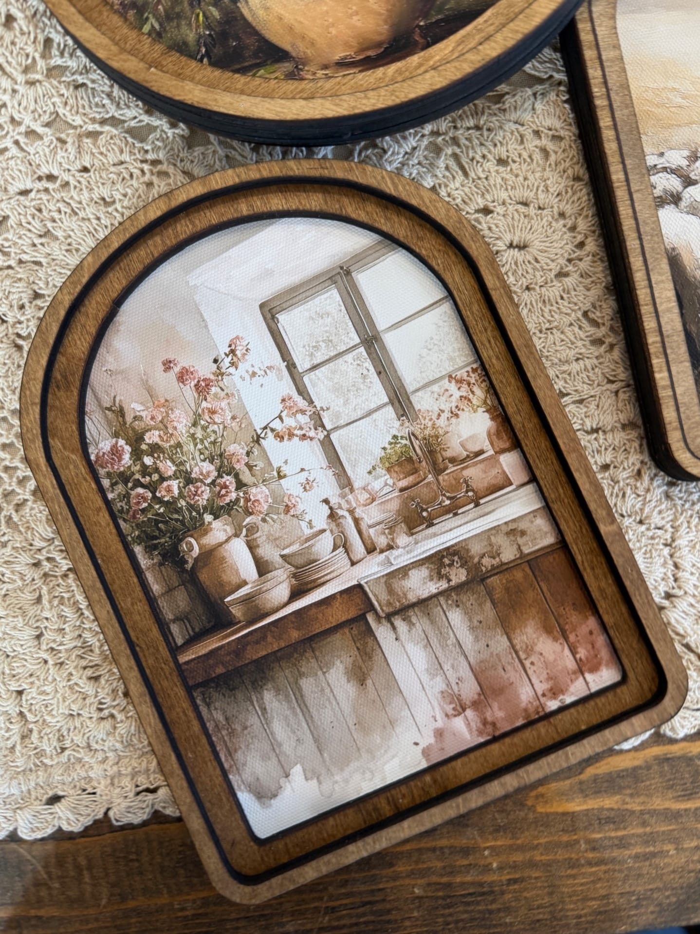 Arched wood framed canvas wall art featuring a rustic kitchen sink scene with florals and vintage details.